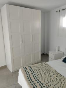 a white bedroom with a bed and white cabinets at APARTAMENTOS TRES SOLES in Écija