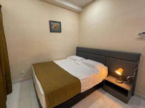 a small bedroom with a bed and a lamp on a night stand at Taiping Modern Home in Kamunting