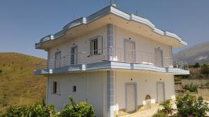 a white building with a balcony on top of it at Vila Antigonea in Gjirokastër