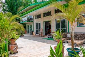 a house with a patio with palm trees and plants at Jungle Jewel in Quepos