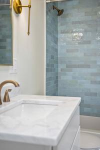 a bathroom with a white tub and blue tiles at Saints Street Charmer in Lafayette +17 photos