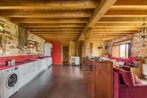 eine große Küche mit roten Möbeln und einer Steinmauer in der Unterkunft El manantial in Liérganes
