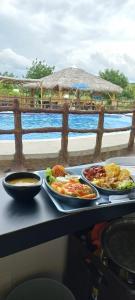 a table with two plates of food on a table with the ocean at Hotel la Isla campestre in Villavieja