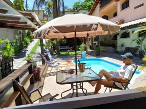 a man sitting in a chair next to a pool at Pousada Nascente do Pirahy in Piraí