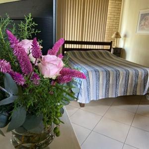 a vase of flowers on a table next to a bed at Pousada Nascente do Pirahy in Piraí