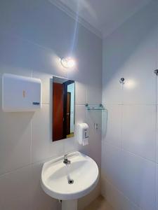 Baño blanco con lavabo y espejo en Hostel Coraticum en Ubatuba