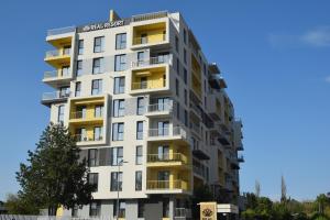 un edificio alto de color blanco con balcones amarillos en Real Resort-Apartament cu 2 camere in cartier rezidential, en Ploieşti