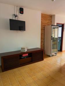 a living room with a television on the wall at Hostel Coraticum in Ubatuba