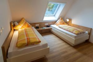 two beds in a small room with a window at Huberhof Pfaffenbach in Gengenbach