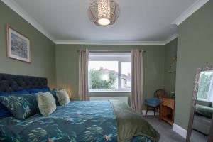 a bedroom with a bed with a blue comforter and a window at Cosy home from home in Bournemouth