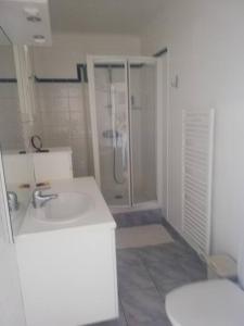 a white bathroom with a shower and a sink at Appartement Saint Raphaël in Saint-Raphaël
