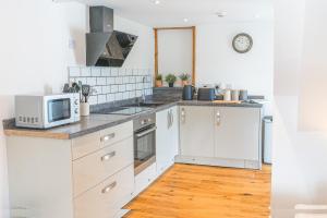 a kitchen with white cabinets and a microwave at The Black Dog Apartment in Dalton in Furness