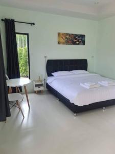 a bedroom with a bed and a table and a window at การ์เด้นวิว รีสอร์ท in Trang