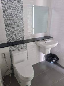 La salle de bains est pourvue de toilettes blanches et d'un lavabo. dans l'établissement การ์เด้นวิว รีสอร์ท, à Trang