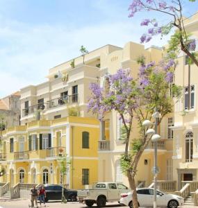 żółty budynek z samochodami zaparkowanymi przed nim w obiekcie beautiful 2 bedrooms apartment with balcony w Tel Awiwie