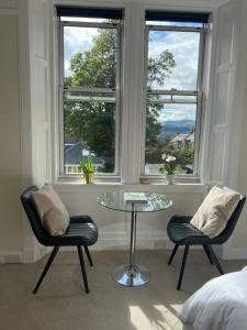 a room with two chairs and a glass table and two windows at Tranquil Haven Murrayfield in Edinburgh