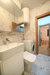 a white bathroom with a sink and a toilet at Apartman Oskar in Podgorica