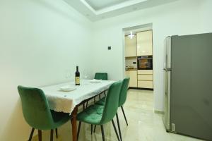 a dining room with a table and green chairs at Apartman Oskar in Podgorica