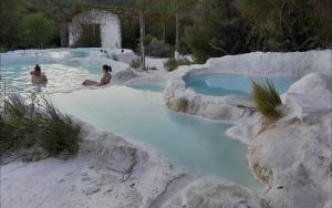 zwei Personen sitzen in einem Pool mit blauem Wasser in der Unterkunft Agriturismo Barbi in Monticchiello