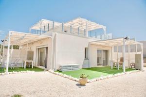 a white house with a green lawn in front of it at Villa Quantum in Siculiana Marina