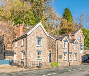 a brick house on the side of a street at Holmleigh cottage in Tintern