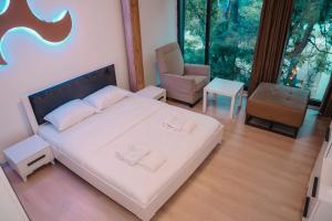 a bedroom with a bed and a chair and a window at Green Apartments Prishtina in Pristina