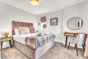 a bedroom with a large bed with two tables and a mirror at Wheatley House in Milton Keynes