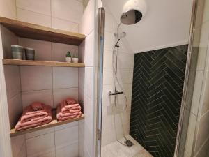 a bathroom with a shower and towels on shelves at B&B Út en thús in Sweagerbosk  +25 photos