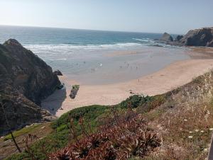 a beach with people on the sand and the ocean at Cute Yellow house at the beach in Praia da Arrifana