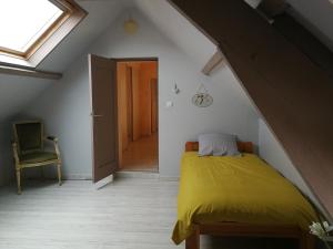 um quarto com uma cama amarela num sótão em AU BON CAUCHOIS em Anglesqueville-lʼ Esneval