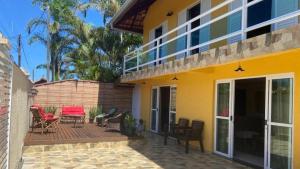 Casa Do Armando في غواراتوبا: منزل أصفر مع شرفة وفناء