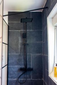 La salle de bains est pourvue d'une douche et d'un mur noir. dans l'établissement Maison d'hôte de l'Aber - Lavande, à Crozon
