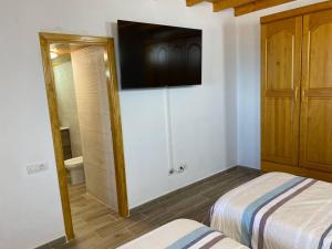 1 dormitorio con 2 camas y TV en la pared en helios casa vacacional, en Puntagorda