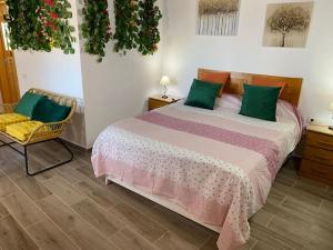a bedroom with a bed with green pillows and a chair at helios casa vacacional in Puntagorda +54 photos