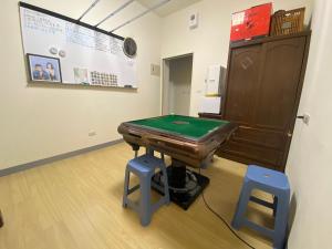 a ping pong table in a room with two blue stools at 康莊背包旅宿 上下舖背包床位4人&6人房&雙人床房-14人包棟-預訂請來電確認 in Ch'ing-tao-ts'un
