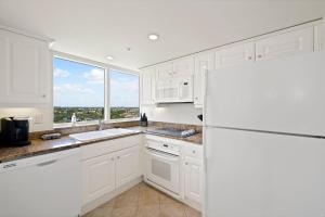 cocina blanca con nevera y ventana en Marco Beach Ocean Suites en Marco Island