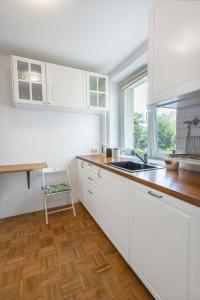 kuchnia z białymi szafkami, umywalką i oknem w obiekcie ClickTheFlat Bellottiego Apart Rooms w Warszawie