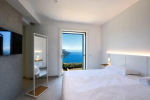 a white bedroom with a large bed and a large window at Hotel Graal in Ravello