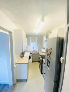 uma cozinha com armários brancos e um frigorífico em London Studio em Chingford
