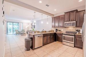 a large kitchen with wooden cabinets and a large island at 3BD Townhouse , Themed , 10 min to Disney , Gated in Kissimmee