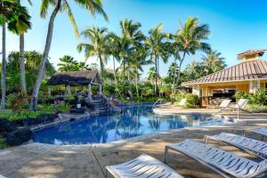 a resort pool with lounge chairs and palm trees at Hale Terra 3br 2ba Beautiful Nihilani Condo, Central AC, Pool, Hot Tub in Princeville