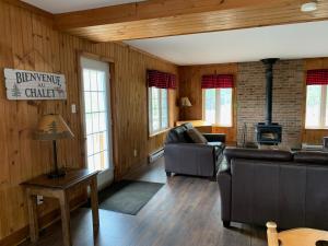 a living room with a couch and a stove at Pourvoirie du Lac Blanc in Saint-Alexis-des-Monts