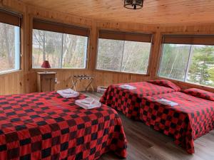 two beds in a room with windows at Pourvoirie du Lac Blanc in Saint-Alexis-des-Monts +58 photos