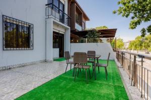 un patio con una mesa y sillas sobre césped verde en Ndussole Guest House 2, en Oporto