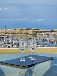 two wine glasses sitting on a table with a marina at MIVE Luxury Sea View Penthouse in Il-Gżira
