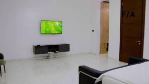 uma sala de estar com televisão numa parede branca em Favourite Luxury Apartment em Ikeja