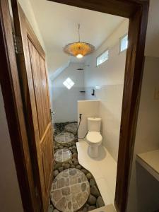 a bathroom with a toilet and some rocks in the floor at MyHome - Lombok in Tetebatu