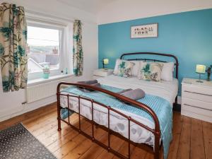 a bedroom with a bed with blue walls and a window at Euryn View in Llandudno