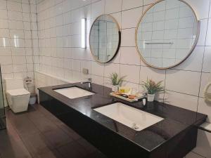 a bathroom with two sinks and two mirrors at E villa near bangtao beach ,普吉高端社区邦涛区度假村私人泳池别墅 in Bang Tao Beach