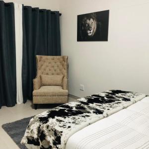 a bedroom with a bed and a chair and a lion picture at 2 bedroom flat in Swakopmund +12 photos